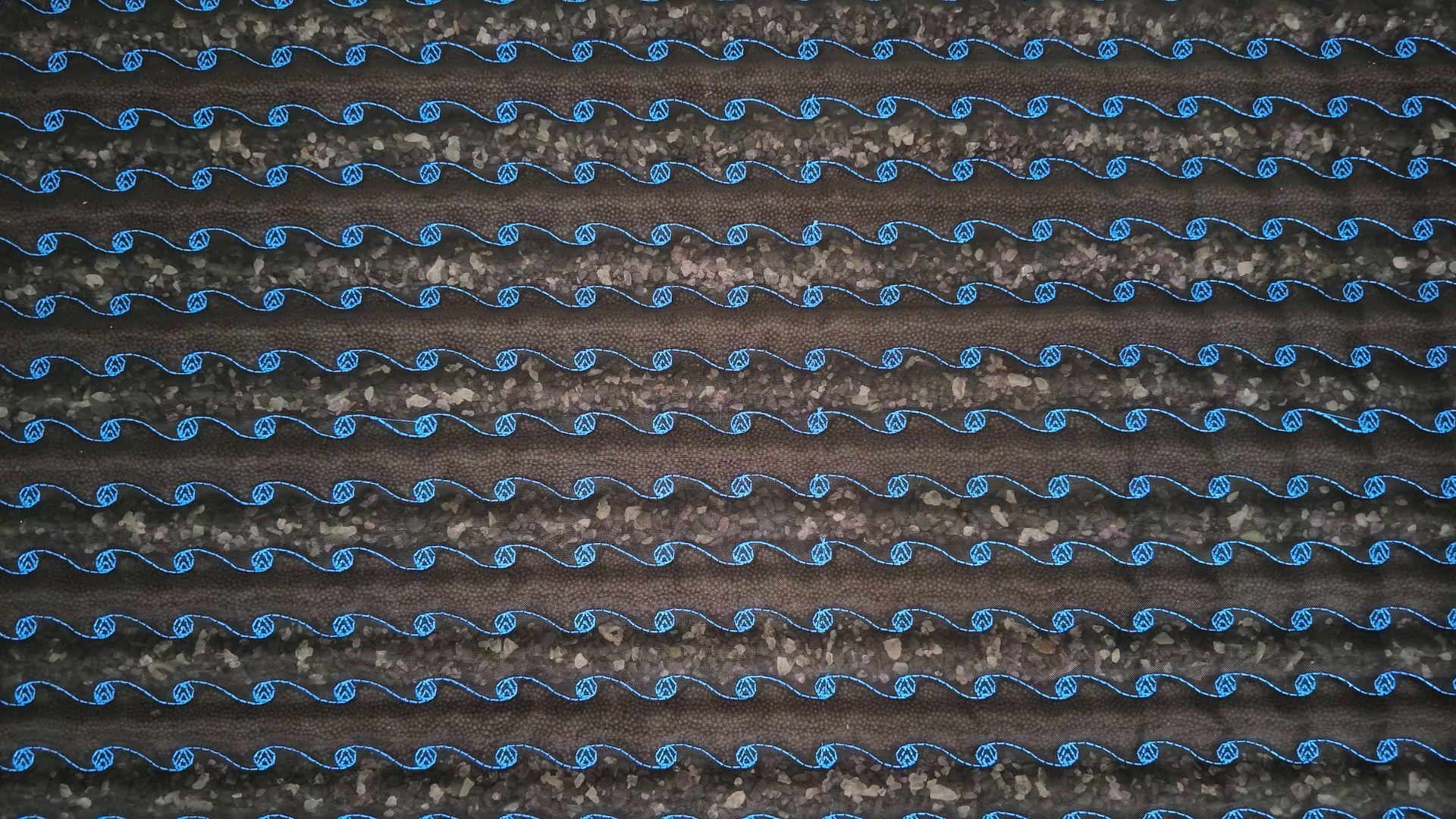 Macro view of tiny polished crystals stitched beneath mesh channels on the PEMF mat