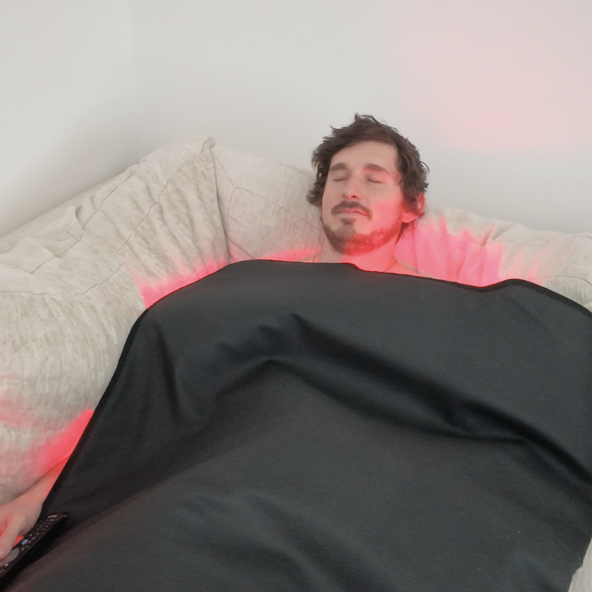 garage biohacker using red light therapy blanket on a sofa